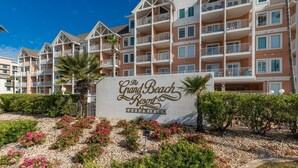 A sign for The Grand Beach Resort Condominium with a multi-story building in the background.