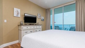 A hotel room with a large bed, a television on a dresser, and a balcony with a view. - Lighthouse 814 2 Bedroom Condo (Gulf Shores)