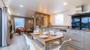 Una cucina moderna con mobili bianchi, un tavolo da pranzo in legno e un forno a incasso.