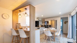Una cucina moderna con piani in legno, sedie bianche e un'isola centrale.