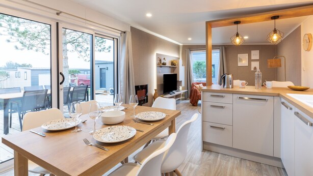 Una cucina moderna con mobili bianchi, un tavolo da pranzo in legno e un'ampia finestra che si affaccia su un giardino.