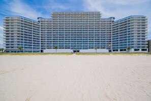 Un grand hôtel à plusieurs étages, doté d’une façade symétrique, de nombreux balcons et offrant une vue sur la plage.