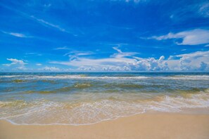 Une plage avec un ciel dégagé et des vagues.