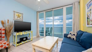 Ein Wohnzimmer mit Fernseher, einer Couch, einem Couchtisch und einem Balkon mit Blick.