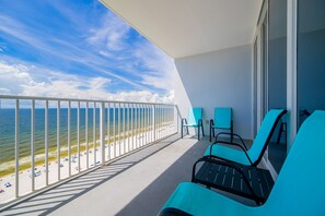 Un balcon avec vue sur la plage et l’océan, équipé de chaises et d’une rambarde.