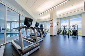 A gym with treadmills, elliptical machines, and stationary bikes. - Lighthouse 1409 1 Bedroom Condo (Gulf Shores)