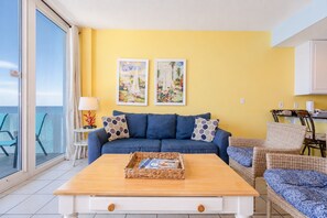 Una sala de estar con un sofá, una mesa de centro con revistas y dos cuadros en la pared.