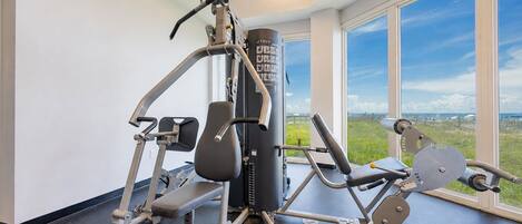 Un gimnasio con equipo de ejercicio, ventanas amplias y vistas al exterior.