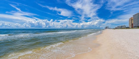 Une plage avec un ciel dégagé et des vagues sur l’océan.