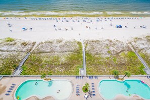 A beach with a pool area, including two swimming pools and a walkway. - Lighthouse 1409 1 Bedroom Condo (Gulf Shores)