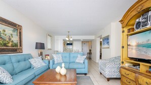 A living room with a blue sofa, a wooden coffee table, and a television on a wooden cabinet.