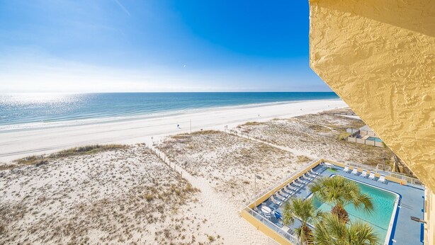 A beach view with a swimming pool and lounge chairs.