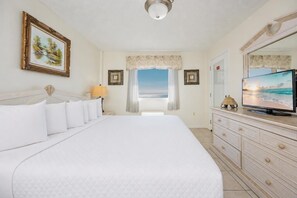 Habitación de hotel con una cama grande, televisor, cómoda y vista al océano.