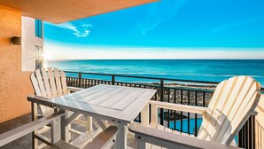 A balcony with a table and chairs, overlooking a beach and ocean. - Sea Chase 505c 3 Bedroom Condo (Orange Beach)