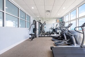 A gym with treadmills, weight machines, and a TV screen. - Crystal Shores West 807 2 Bedroom Condo (Gulf Shores)