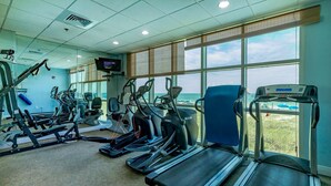 A gym with treadmills, elliptical machines, and weight machines, large windows with a view of the beach. - Crystal Shores West 807 2 Bedroom Condo (Gulf Shores)