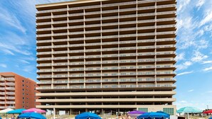 A high-rise hotel with multiple balconies, a flat roof, and a beachside location with umbrellas and beach chairs. - Crystal Shores West 807 2 Bedroom Condo (Gulf Shores)