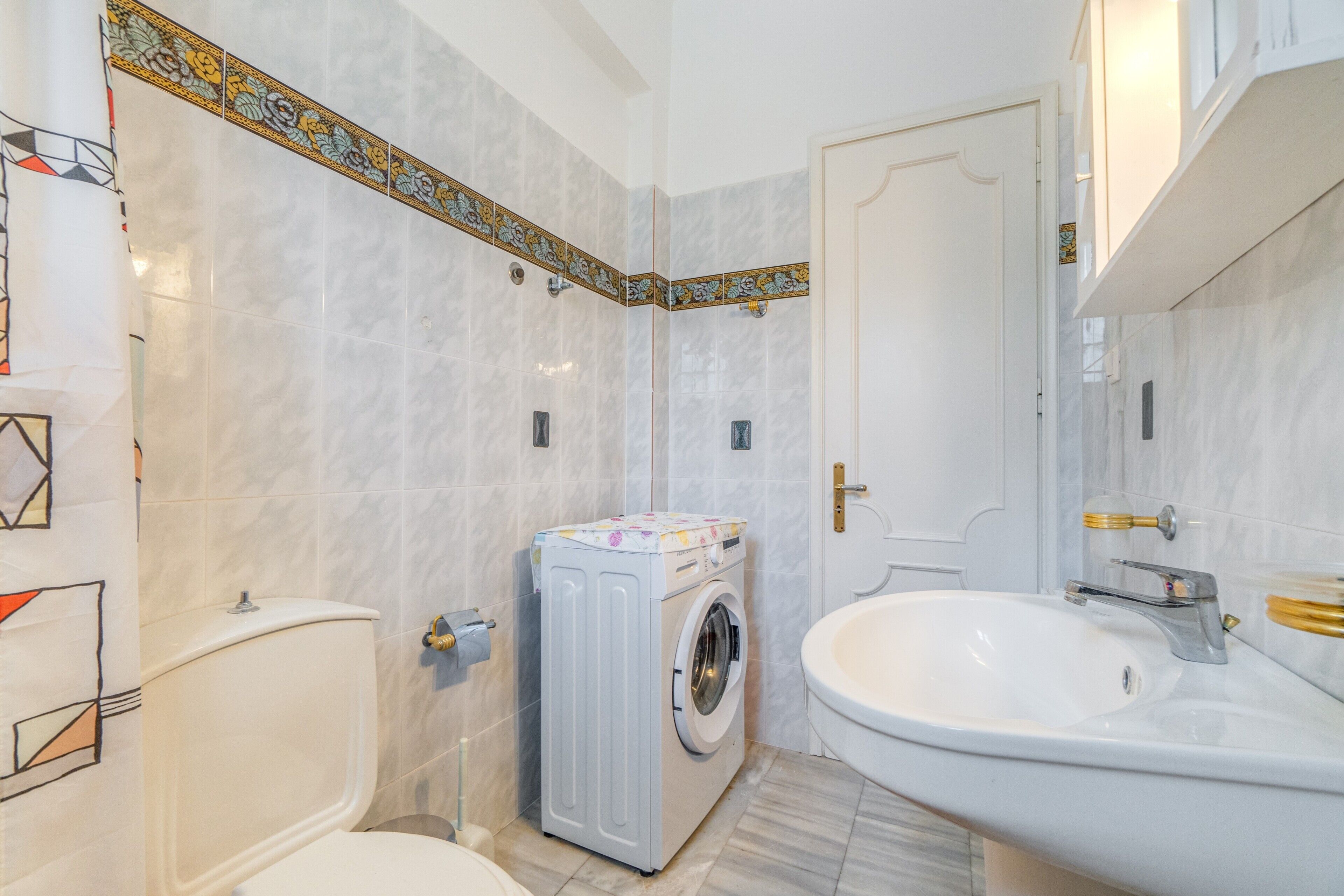 Un baño con inodoro, lavadora y lavabo.