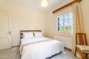Une chambre à coucher avec un lit, une chaise, une fenêtre avec des rideaux et un radiateur.