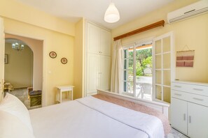 Ein Schlafzimmer mit Bett, Kleiderschrank, Fenster mit Blick und einem kleinen Tisch.