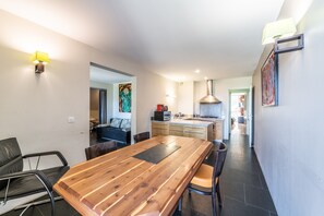 A modern kitchen with a central island, wooden dining table, and chairs.