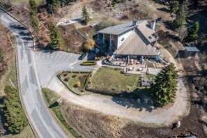 Vue aérienne d’un bâtiment doté d’un toit en pente, d’un espace de stationnement et d’un jardin aménagé.