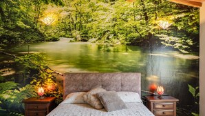 Ein Schlafzimmer mit einem Bett, zwei Nachttischen und einem Wandgemälde eines Waldlaufs.