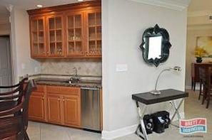 A kitchen with wooden cabinets, a built-in dishwasher, and a black countertop with a mirror above it.