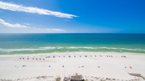 A beach with a wooden pier, clear blue sky, and calm sea.