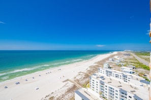 A beach view with a hotel, clear skies, and ocean.