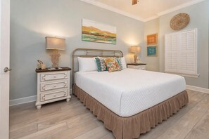 A bedroom with a bed, nightstands, a dresser, and wall art.