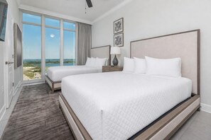 Et hotelværelse med to senge, et stort vindue med udsigt, et sengebord og en lampe.