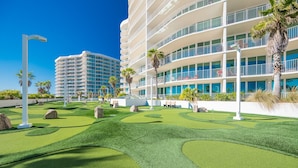 Un hotel moderno con una estructura de varios pisos, césped cuidado y palmeras.