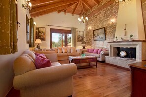 Una sala de estar con piso de madera, chimenea y pared de piedra.