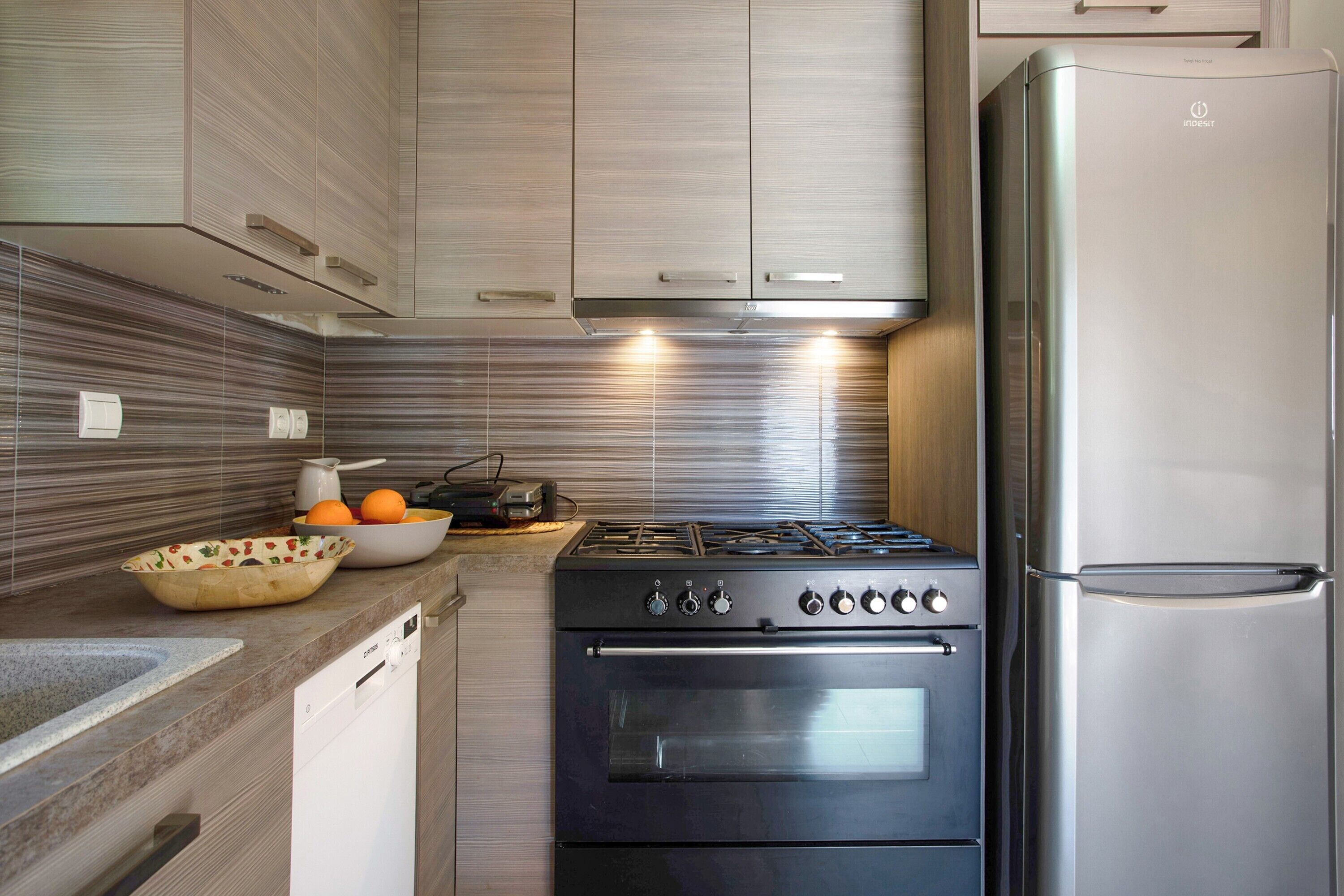 Una cocina con un refrigerador de acero inoxidable, una estufa a gas y un lavavajillas.