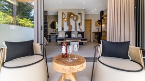 Een modern interieur met een ronde houten tafel, twee stoelen, een fles en twee glaasjes.