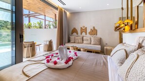 A modern hotel room with a large bed, a sofa, a dining area, and a view of greenery outside. - Studio Apartment 'Studio Yvonne' with Private Pool, Wi-Fi and Air Conditioning (Meganisi)