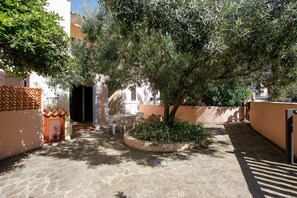 Un patio con suelo de piedra, un árbol y una pequeña zona de estar.