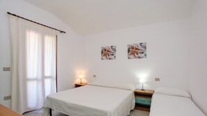 Ein Schlafzimmer mit zwei Betten, einem Holztisch und zwei Wandlampen.