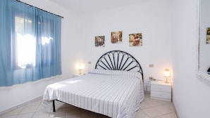 Un dormitorio con cama, mesita de noche, lámpara, ventana con cortinas y decoración en la pared.