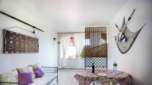 A room with a bed, a table with chairs, a hammock, and a decorative wall hanging. - Holiday Home "mirtagru Bilo Mare 2" with Sea View, Private Terrace and Wi-Fi (Budoni)