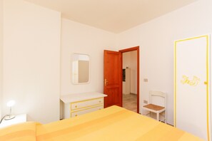 Une chambre à coucher avec un lit, une commode, un miroir, une porte et une chaise.
