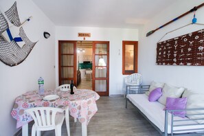 Une pièce comprenant une table à manger, des chaises, un canapé, une étagère fixée au mur et une porte portant l’inscription « NORDHL ».