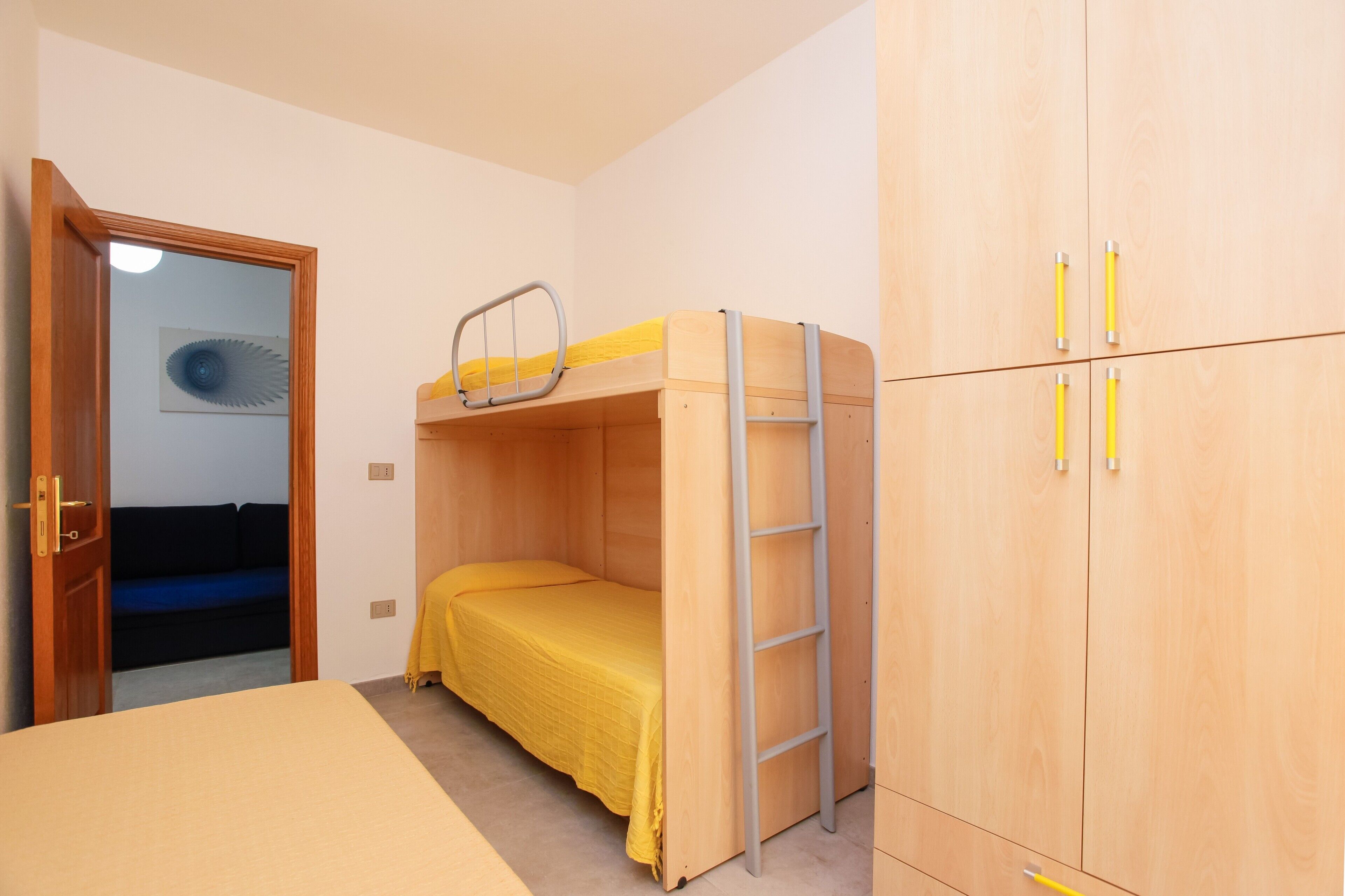 Ein Zimmer mit einem Etagenbett, einem Kleiderschrank und einer Tür zu einem anderen Raum.