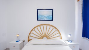 Ein Schlafzimmer mit einem Bett, zwei Nachttischen mit Lampen, einem Holzkopfteil, einem gerahmten Bild an der Wand und einem blauen Vorhang.