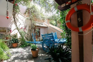 A courtyard with a blue cart, potted plants, and a life preserver.