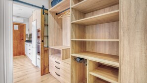 Interior de madera con una puerta corredera que da a una cocina, cajones empotrados y estanterías abiertas.