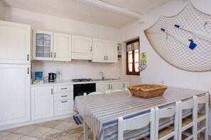 A kitchen with white cabinets, a stove, and a dining table with a striped tablecloth.
