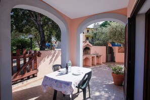 Une terrasse avec une table dressée pour deux personnes, une clôture en bois et une plante en pot.