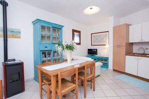 A modern kitchen with a dining area, a blue cabinet, a white refrigerator, and a wood-burning stove.
